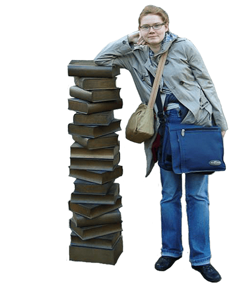 Ewa Młynarczyk podparta o rzeźbę w kształcie stosu książek, opracowująca w myślach kolejne artykuły